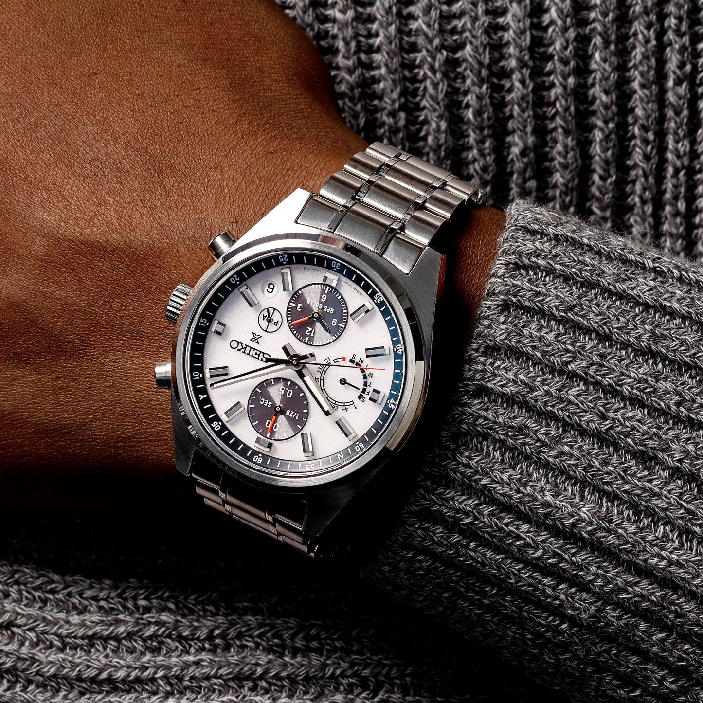 Silver wristwatch with a detailed face on a textured surface